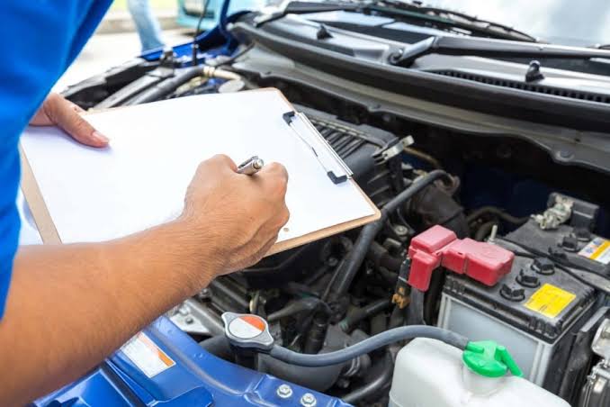 Mechanic performing a log book service inspection under the hood